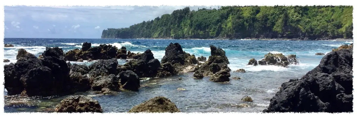 Waves breaking over lava rocks and tide pools at Laupāhoehoe Point, with sea cliffs along the Hāmākua Coast.