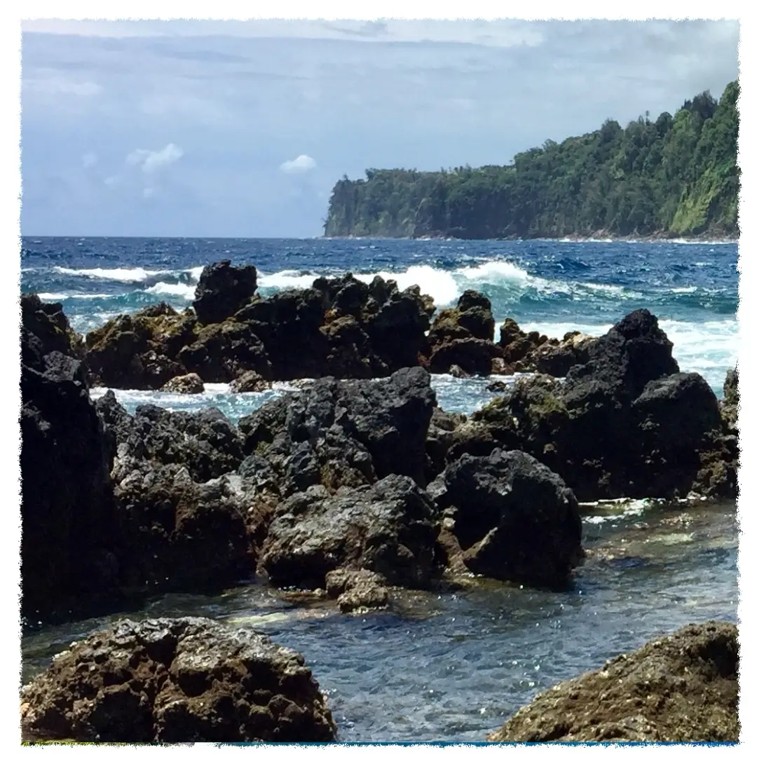 Waves breaking over lava rocks and tide pools at Laupāhoehoe Point, with sea cliffs along the Hāmākua Coast.